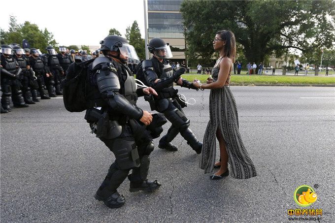 事件发生于7月9日，一名黑人女子在巴吞鲁日参加抗议示威，她穿着一条黑色长裙，独自站在街上。面对一整排的防暴警察，她看起来相当平静，有2名全副武装的警员上前准备将她压制逮捕，但她却毫无惧色，警民对峙形成强烈对比。