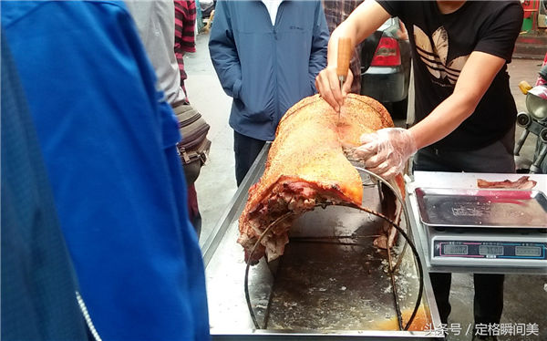 图为卖主为市民切割烤熟脆皮猪肉。